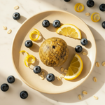Lemon Blueberry Oatball on a plate with fresh blueberries and lemon slices